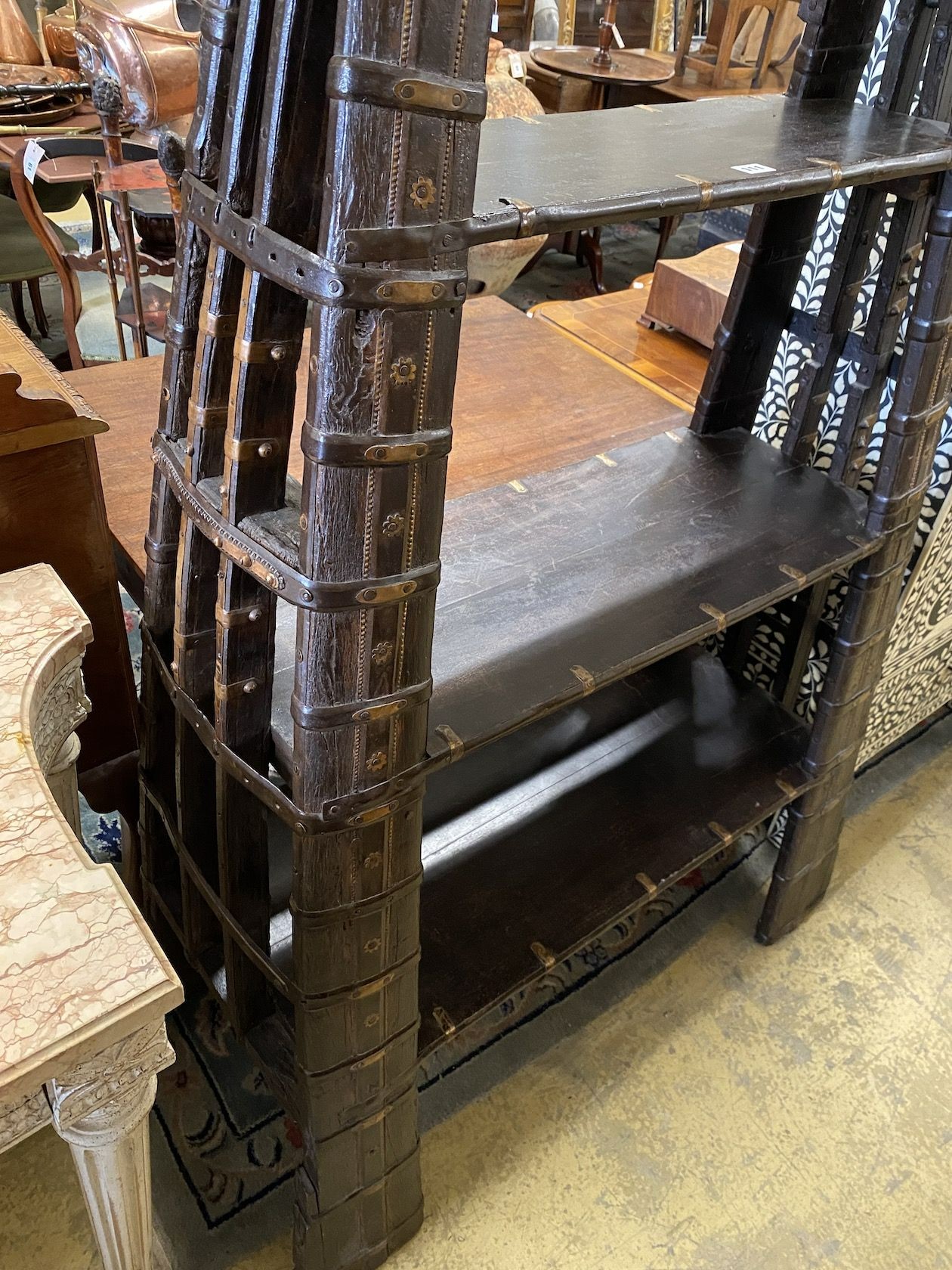 An Indian brass mounted carved hardwood three tier shelf unit, constructed from a 19th century ox harness, length 106cm, depth 40cm, height 202cm